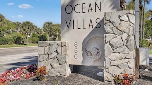 A sign for Ocean Villas with a stone wall and a spiral design. - Ocean Villas 108: Top floor 3 bedroom condo in gated complex - 2 pools, beach (St. Augustine Beach)