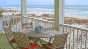 A wooden deck with a table and chairs, overlooking a beach and ocean. - Luxury Beachfront Home with Extra Large Deck;  Sleeps up to 20! (Gulf Shores)
