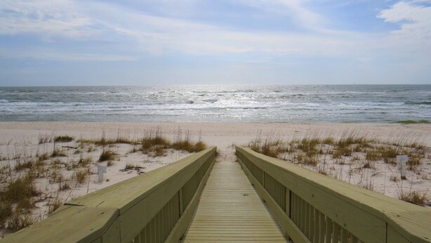 A wooden boardwalk leading to a beach with sand and sparse grass. - Luxury Beachfront Home with Extra Large Deck;  Sleeps up to 20! (Gulf Shores)