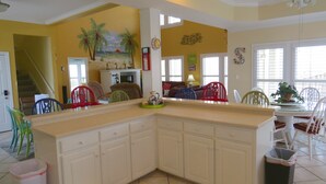 A kitchen with a large island, yellow walls, and a mural of palm trees. - Luxury Beachfront Home with Extra Large Deck;  Sleeps up to 20! (Gulf Shores)