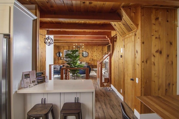 A wooden interior with a kitchen area, a dining table, and a staircase.