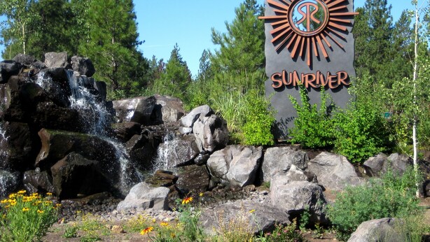 A waterfall, rocks, and a sign with the word "SUNRIVER".