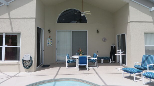 A covered outdoor area with a pool, lounge chairs, and a table with chairs. - 5 BR/4 BA/2-Floors/Keyless Entry/Contactless Check-In/1-Day Between Rentals/WiFi (Kissimmee)