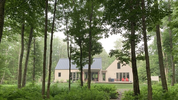 A cabin in a forest with a dirt path leading to it.
