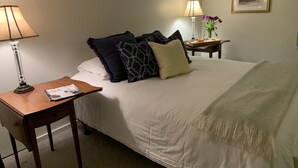 A neatly arranged bedroom with a bed, bedside tables, lamps, and a framed picture on the wall.