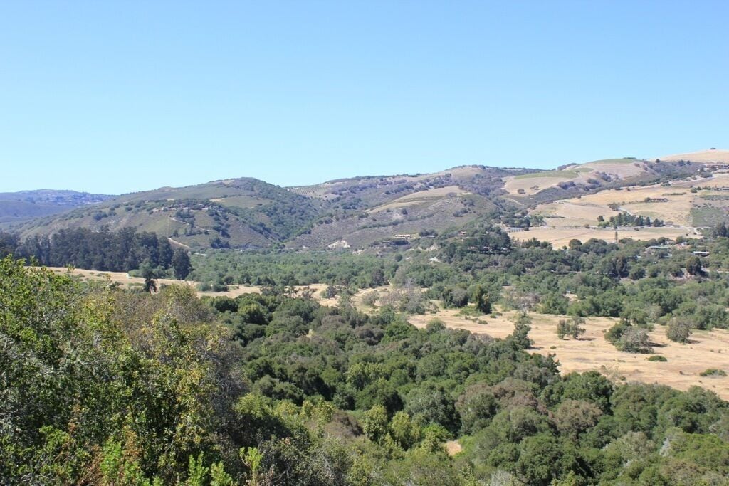 Un paisaje montañoso con abundante vegetación y edificios dispersos.