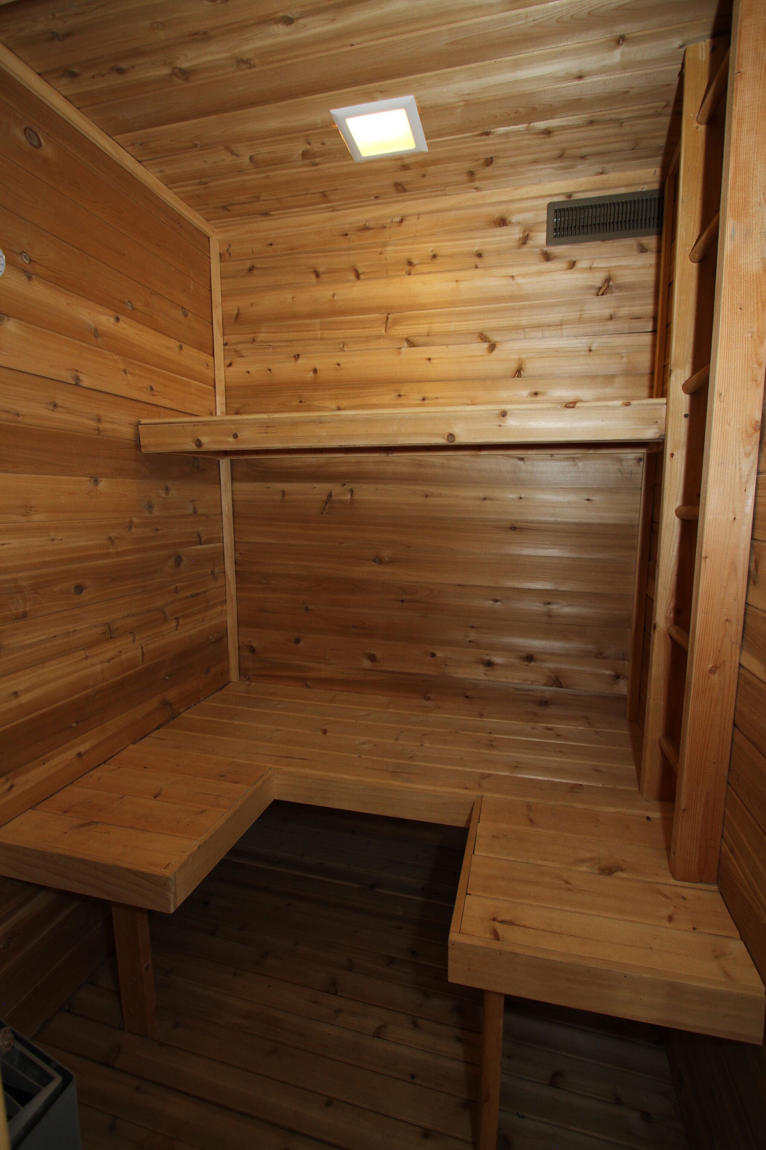 Una sauna de madera con bancos y techo inclinado.