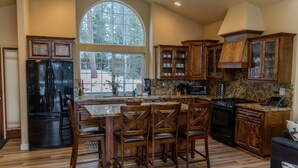 A spacious kitchen with a large island, wooden cabinets, and a black refrigerator.