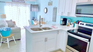A compact kitchen with white cabinets, a built-in microwave, and a coffee maker. - 2-Story Beach-side Complex with Direct Beach Access, Book Your Beach Getaway! (Indian Rocks Beach)