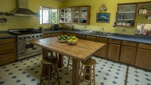 Une cuisine avec une table en bois, des tabourets, une cuisinière et des placards.