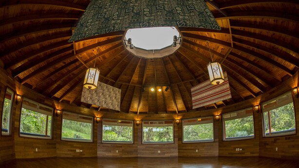 Une pièce spacieuse avec un plafond haut, de grandes fenêtres et des murs en bois.