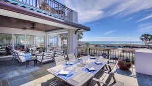 Un balcon avec une table dressée pour le dîner, offrant une vue sur une plage et l’océan.