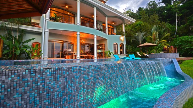 Une grande maison avec une piscine, un patio couvert et un jardin luxuriant.