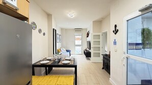 A modern kitchen with a dining table set for four, a built-in oven, and a bench with a yellow cushion. - ⭐️Best XL Valencia Beach Flat♜ Historic Area♜Beach (Valencia)