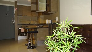 A modern kitchen with a bar area, wooden cabinets, and a potted plant. - Moneda Express Apart (Santiago)