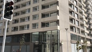 A high-rise building with multiple balconies and a ground-level entrance with glass doors. - Moneda Express Apart (Santiago)