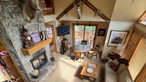 A spacious living area with a stone fireplace, leather furniture, and a mounted deer head.