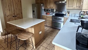 A kitchen with wooden cabinets, a stainless steel refrigerator, a microwave, an oven, and a coffee maker.