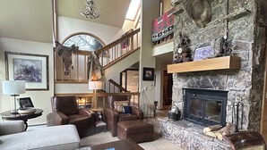 A spacious living room with a fireplace, leather furniture, and a stone accent wall.