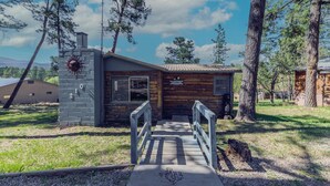 A rustic cabin with a stone chimney, wooden walls, and a small porch. - Happy Days Inn | Your Happy Place in the Pines w/ Hot Tub,Views & Pet Friendly (Ruidoso)