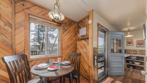 A wooden interior with a dining table, chairs, and a window. - Happy Days Inn | Your Happy Place in the Pines w/ Hot Tub,Views & Pet Friendly (Ruidoso)