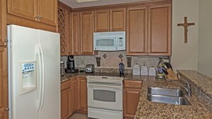 A kitchen with wooden cabinets, a white refrigerator, a microwave, a stove, and a sink. - Gorgeous Oceanfront 3Bedroom Away From The Hustle and Bustle (St Augustine)