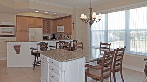 A kitchen with a central island, wooden cabinets, and a large window. - Gorgeous Oceanfront 3Bedroom Away From The Hustle and Bustle (St Augustine)