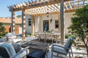 Une terrasse extérieure dotée d’une pergola, d’un espace salon et d’un foyer.