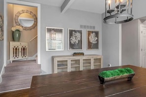 A dining area with a wooden table, a green plant centerpiece, and framed botanical prints on the wall.