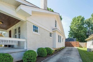 Une maison de plain-pied avec un porche couvert, une cheminée et une cour clôturée.