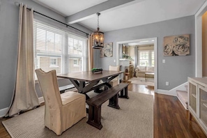 A dining area with a wooden table and chairs, a bench, and a hanging light fixture.