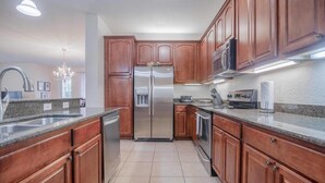 Una cocina moderna con armarios de madera, electrodomésticos de acero inoxidable, encimeras de granito y una araña.