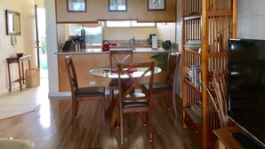 A kitchen with wooden cabinets, a dining table with chairs, a ceiling fan, and a bookshelf. - KAILANI at Mauna Loa Shores, Fantastic Condo, Swim with the Sea Turtles (Hilo)