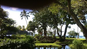 A serene garden with a pond, lush greenery, and a view of the ocean. - KAILANI at Mauna Loa Shores, Fantastic Condo, Swim with the Sea Turtles (Hilo)