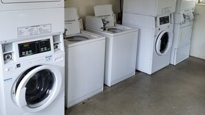 A laundry room with multiple stacked washing machines and dryers, a ceiling fan, and a 'No Smoking' sign on the wall. - Two Bedroom One Bath Apartment(sleeps no more than 4) (Mariposa)