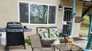 A patio area with outdoor furniture, a grill, and a bear statue. - Two Bedroom One Bath Apartment(sleeps no more than 4) (Mariposa)