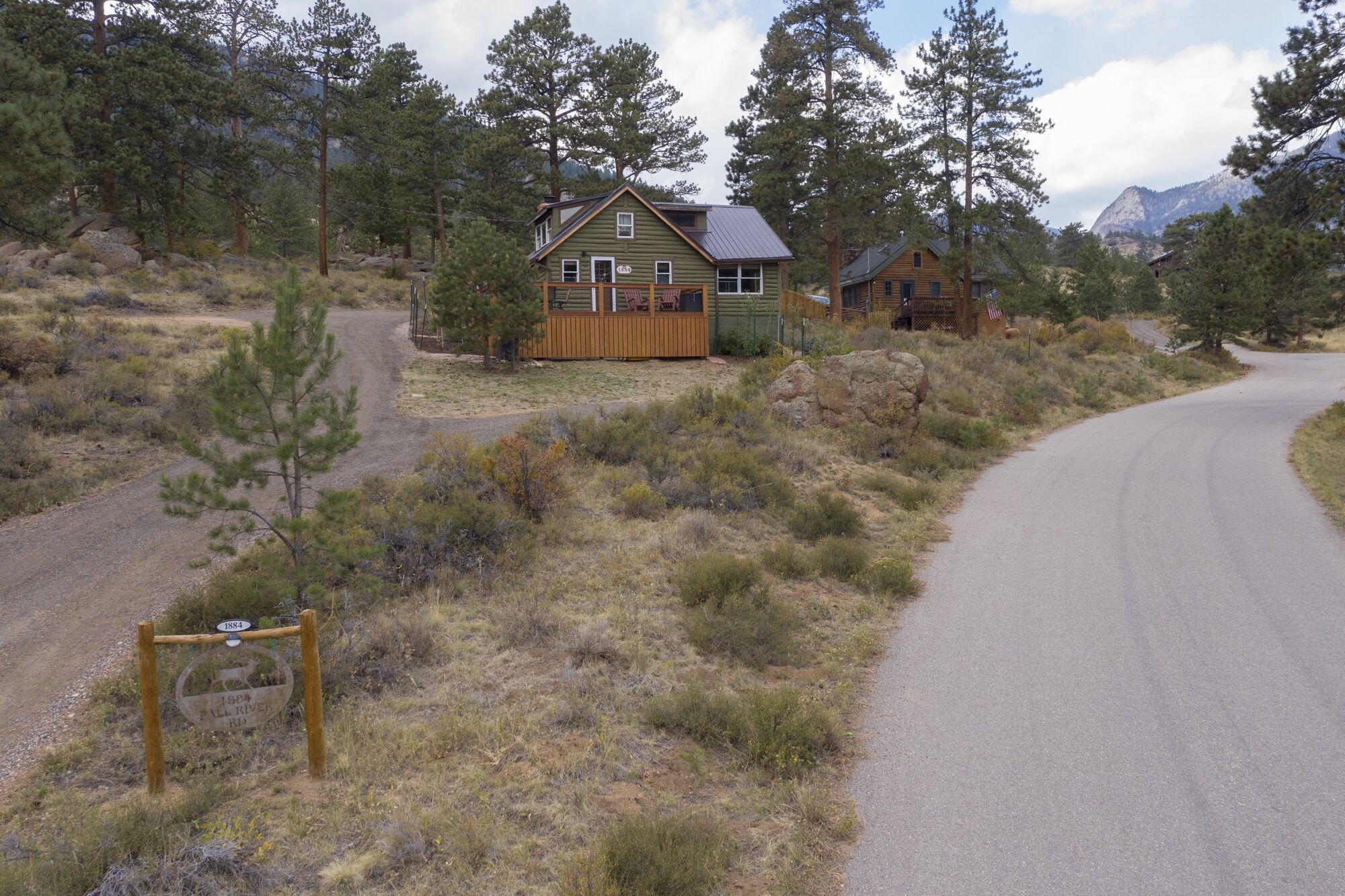 A rustic cabin with a wooden deck and a dirt path leading to it.
