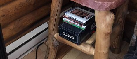 A wooden table with a lamp, a woven basket, a stack of books, and a phone.