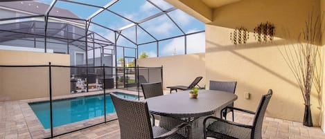 A covered patio with a pool, outdoor furniture, and a view of the surrounding area.