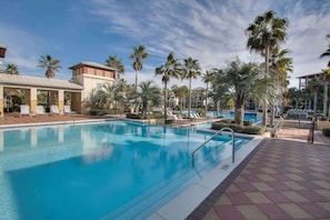 A swimming pool with lounge chairs, palm trees, and a covered area. - Overlooks Lagoon Pool - 4 Bikes-New Reno-Elevator (Panama City Beach)
