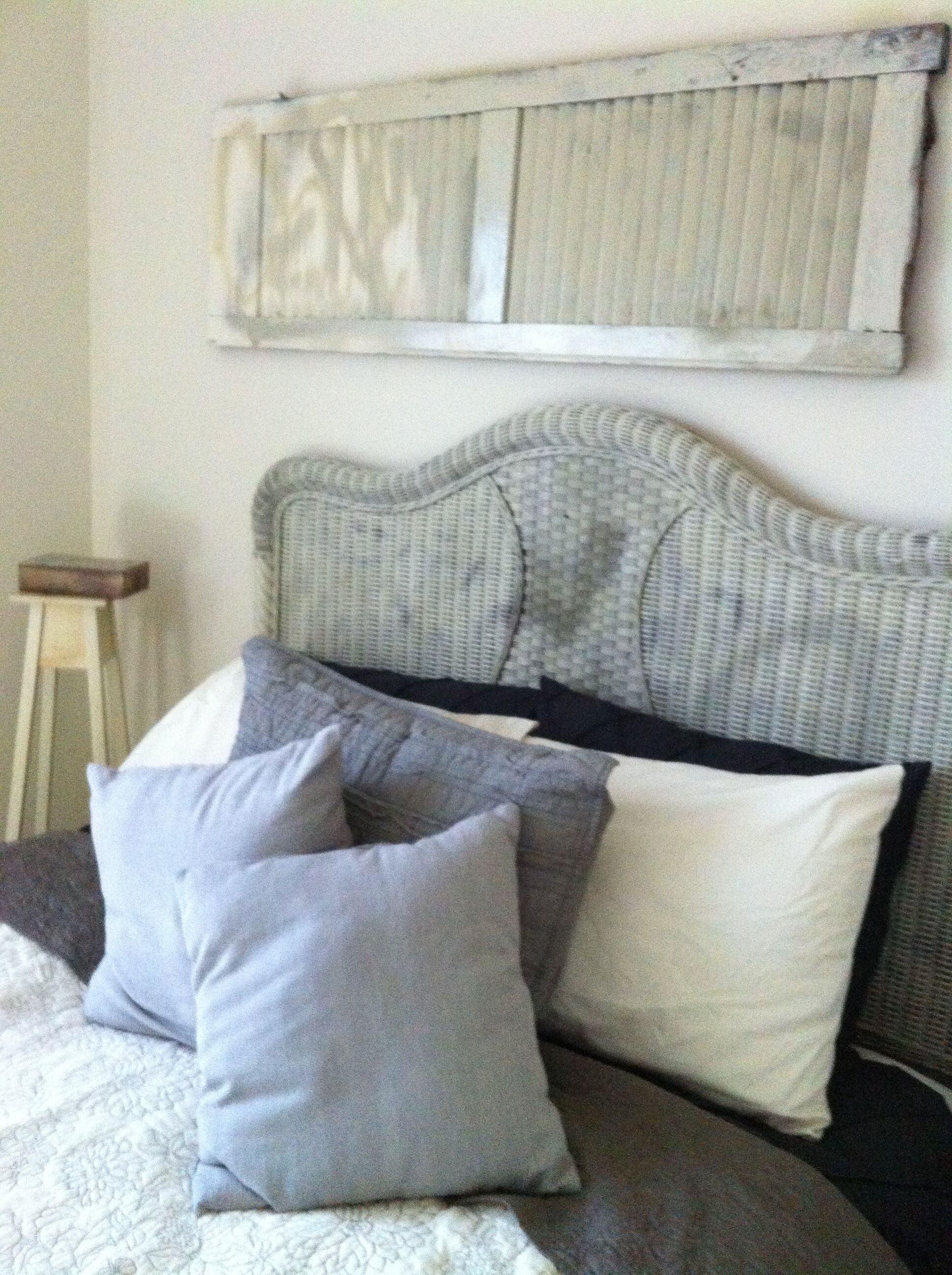 A bed with a grey headboard, grey and white pillows, and a white bedspread.
