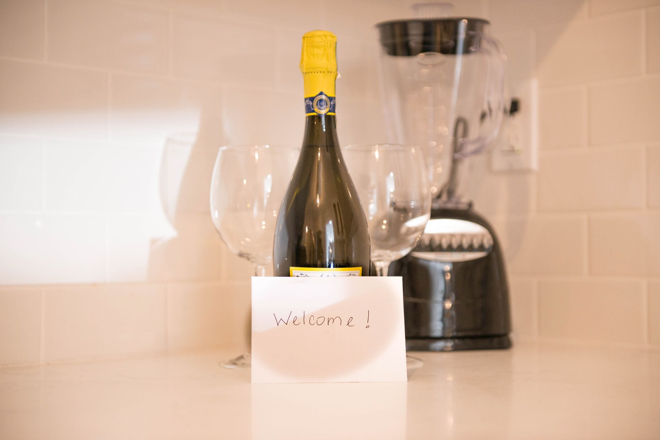 A bottle of champagne with a "Welcome!" sign in a kitchen setting.