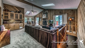 A spacious living area with a long sofa, wooden cabinets, and a fireplace.