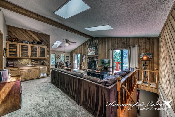 A spacious living area with a long sofa, wooden cabinets, and a fireplace.