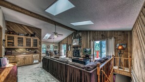 Un espacio habitable amplio con un sofá grande, armarios de madera y una chimenea.
