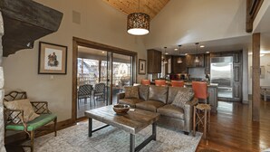 A spacious living area with a wooden ceiling, a large sofa, a coffee table, and a kitchen in the background. - Incredible luxury townhome in downtown Whitefish! 1 block from all downtown shops and restaurants (Whitefish)