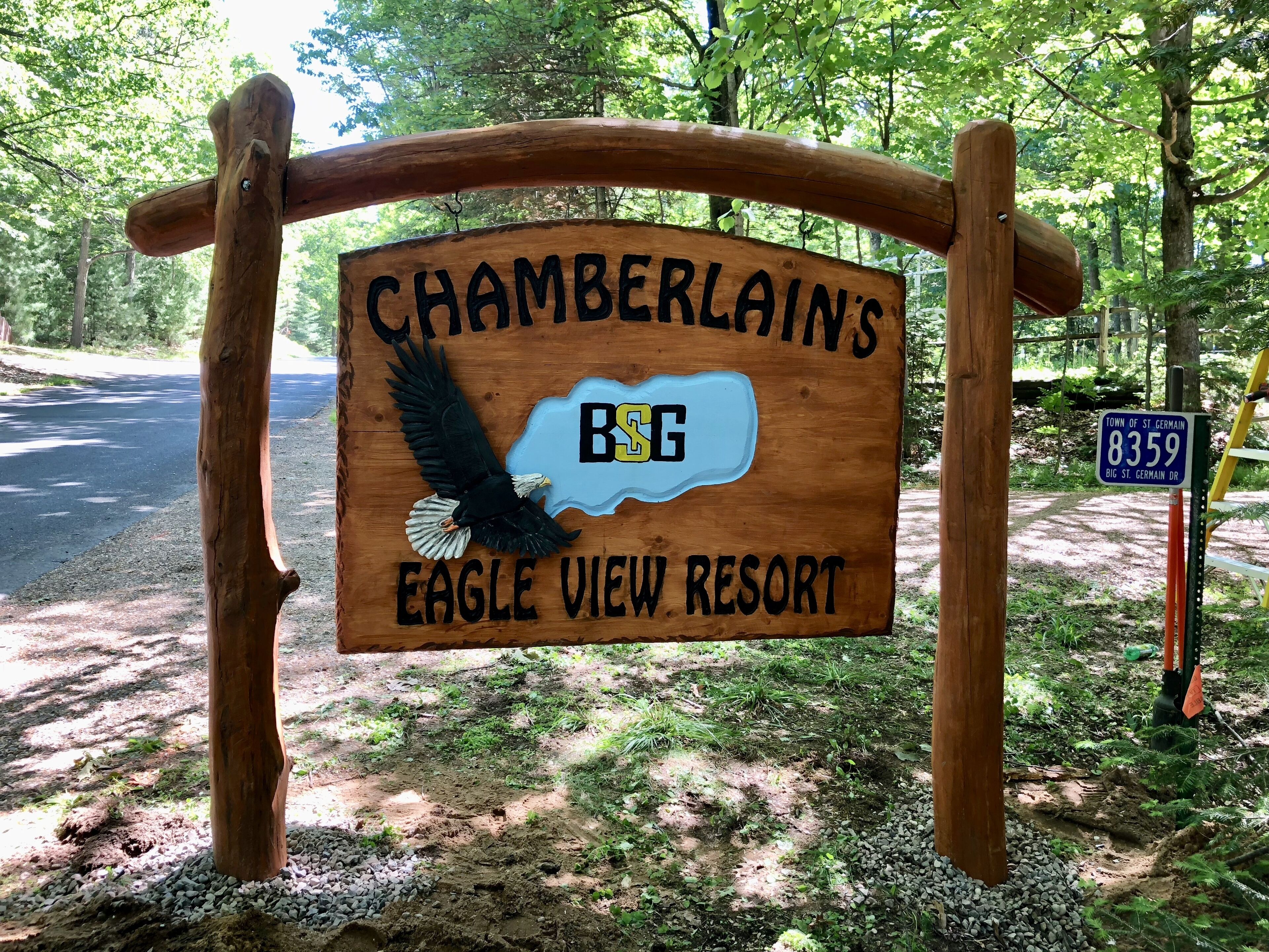 Een houten bord voor Chamberlain's Eagle View Resort met een vogel logo en het BSG logo.