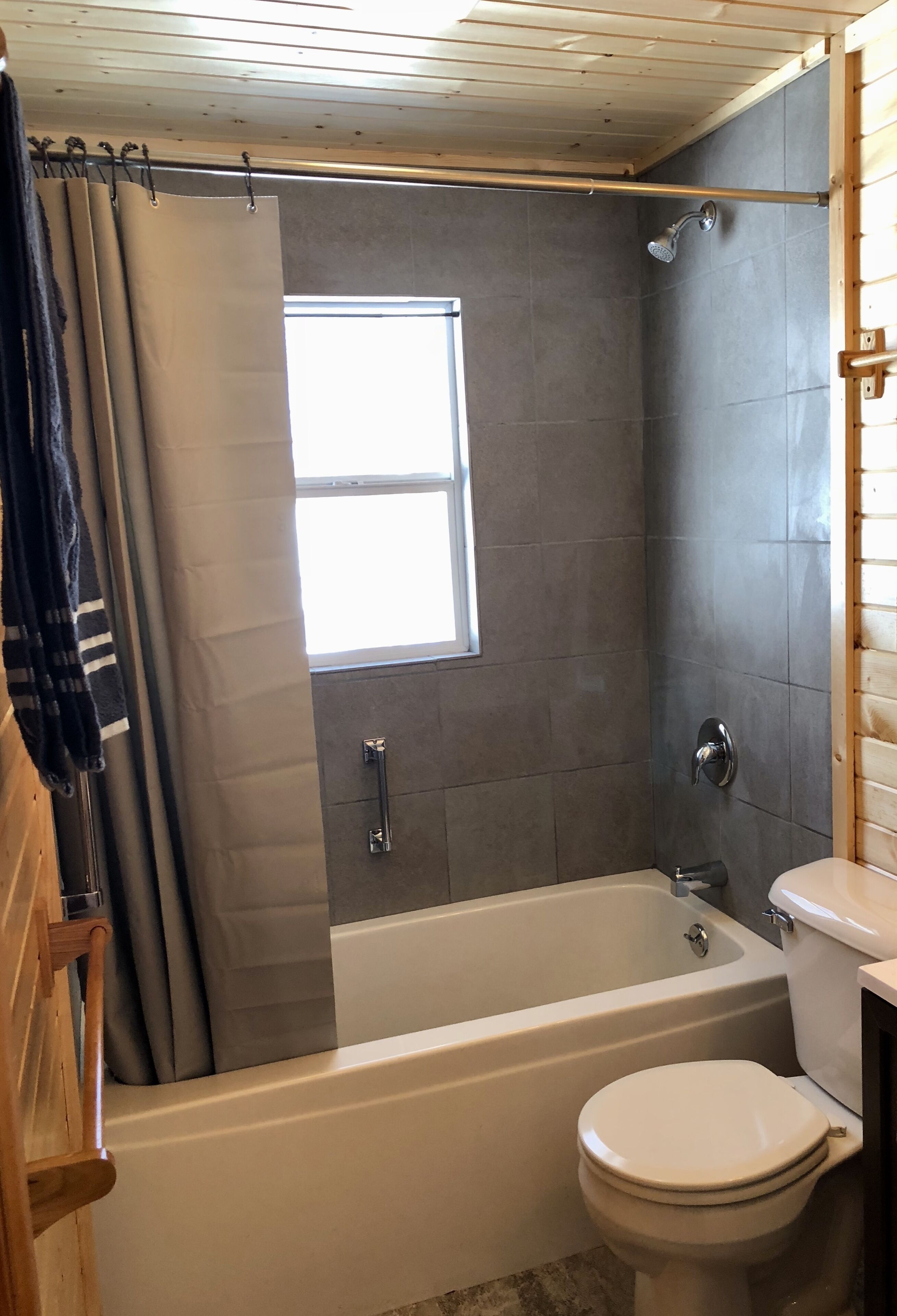 A bathroom with a bathtub, toilet, and a window.