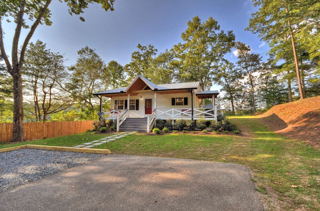 A two-story house with a front porch, a small staircase, and a driveway.