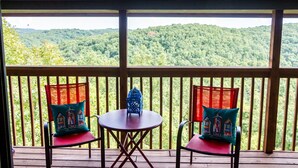 A wooden deck with two chairs and a table, overlooking a forested hillside. - Romantic getaway with a view; close to SDC and the Branson Strip (Branson West)